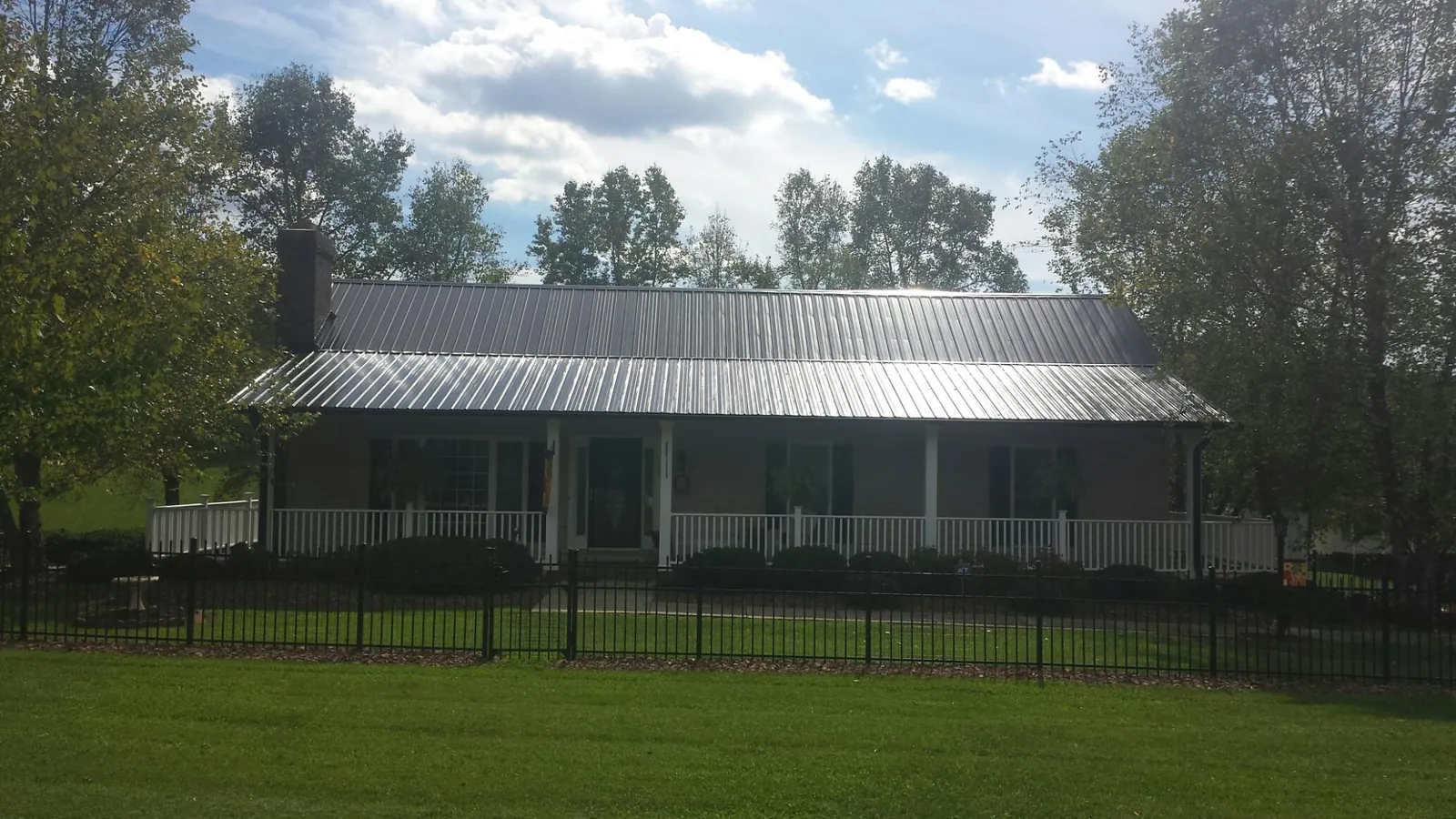 Gray metal roof on a brick ranch with a full width front porch — Gutter Guard Installation work by our crew in Leesburg